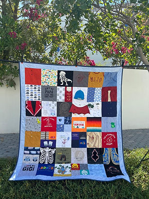 Memory quilt, bear and cushion arranged together on a couch