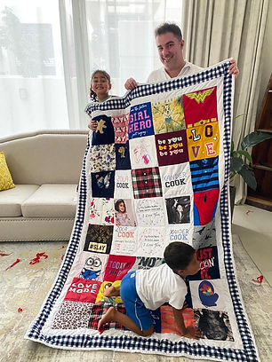 A family holding a handmade memory quilt made from their loved one's clothes